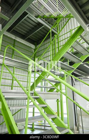 Escalier industriel en métal avec garde-corps verts dans l'entrepôt moderne Banque D'Images