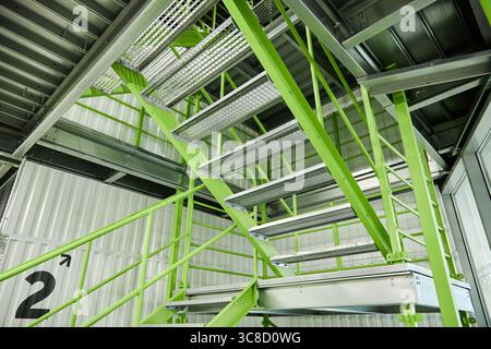 Escalier industriel moderne avec marches en métal vert dans l'intérieur de l'entrepôt Banque D'Images