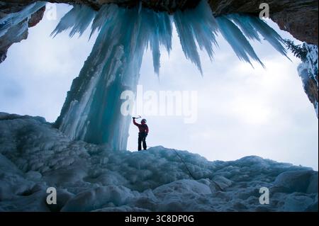 Grimpeur de glace testant la qualité sur un pilier de glace. Banque D'Images