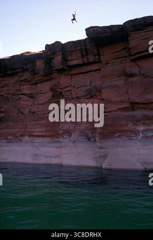 Brian Miller sautant d'une grande falaise dans les eaux du lac Powell par une chaude journée d'été. Banque D'Images
