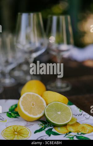 Table à manger élégante décorée de citrons, citron vert, serviette colorée et verres à vin élégants. Pièce maîtresse d'agrumes frais, design rustique et moderne. Banque D'Images