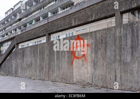 Peinture rouge pulvérisée symbole / signe anarchie sur le mur adjacent aux appartements appartenant au conseil à Southampton, Hampshire, Angleterre, Royaume-Uni Banque D'Images