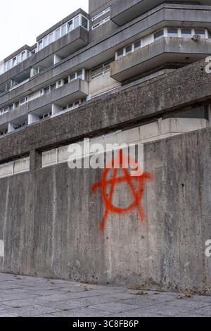 Peinture rouge pulvérisée symbole / signe anarchie sur le mur adjacent aux appartements appartenant au conseil à Southampton, Hampshire, Angleterre, Royaume-Uni Banque D'Images