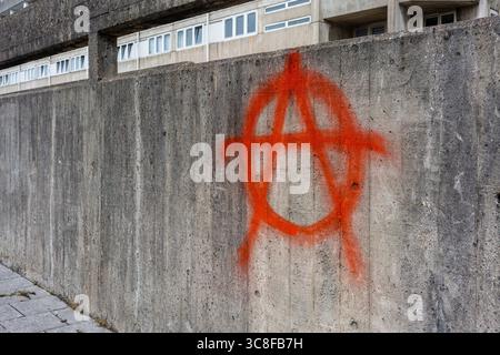 Peinture rouge pulvérisée symbole / signe anarchie sur le mur adjacent aux appartements appartenant au conseil à Southampton, Hampshire, Angleterre, Royaume-Uni Banque D'Images