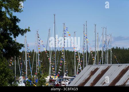 Voiliers avec des drapeaux vibrants amarrés dans le port par une journée d'été lumineuse Banque D'Images