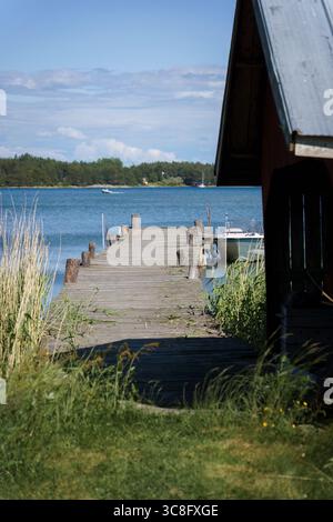 Quai en bois à côté d'un hangar à bateaux traditionnel dans l'archipel finlandais en été Banque D'Images