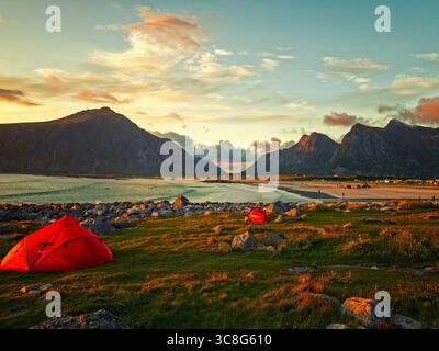 Camping à Skagsanden Beach Sunset. Deux tentes rouges dressées sur un rivage herbeux avec un magnifique coucher de soleil sur la plage de Skagsanden et sa montagne spectaculaire Banque D'Images