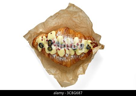 délicieux croissant aux myrtilles sur papier parchemin beige isolé sur fond blanc. Banque D'Images