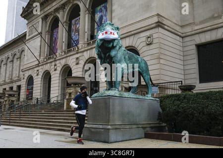 21 janvier 2021, USA : un jogger court devant un des lions de l'Art Institute portant un masque facial le 30 avril 2020 à Chicago. (Crédit image : © TNS via ZUMA Wire) Banque D'Images
