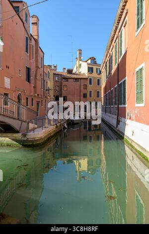 Canal calme à Venise (Venezia), Italie, avec des façades colorées et des reflets dans l'eau, typique de l'architecture résidentielle dans la ville historique c Banque D'Images