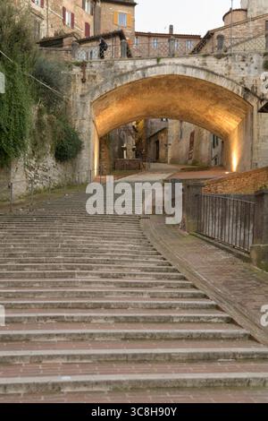 Vue sur l'aqueduc médiéval de Pérouse, montrant l'escalier en pierre et l'arche menant à travers les rues étroites de la ville, illuminé Banque D'Images