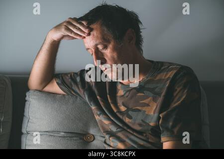 Portrait d'un homme pensif d'âge moyen repensant dans une pièce sombre la nuit, mise au point sélective Banque D'Images