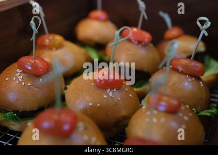 Mini-hamburgers frais sur un plateau déservé contre un mur de briques. Photo de haute qualité Banque D'Images
