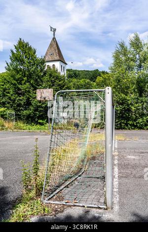 Vieux terrain de sport avec surface asphaltée, mauvaises herbes récupérant l'espace, terrain de football apparemment abandonné à Schmallenberg-Dorlar, Hochsauerlandkreis distri Banque D'Images