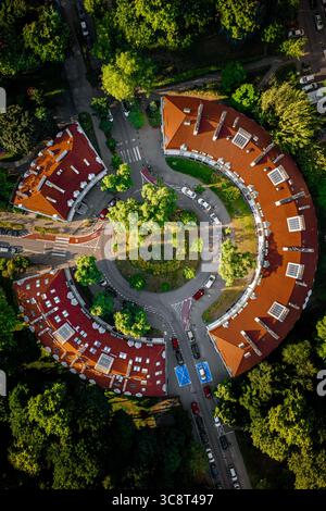Vue aérienne d'un bâtiment semi-circulaire saisissant aux toits rouges niché au milieu d'arbres verdoyants, une oasis urbaine unique, Varsovie, Pologne. Banque D'Images