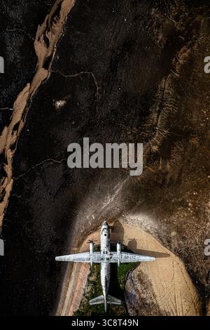 Vue aérienne d'un avion altéré reposant au milieu du contraste saisissant de la terre sombre et fissurée et de la lumière, chemins graveleux, créant un récit visuel saisissant, la Pologne. Banque D'Images