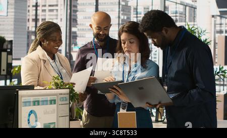 Collègues au bureau effectuant des séances de brainstorming, examinant les graphiques financiers, analysant les indicateurs de performance de l'entreprise. Collègues travaillant en équipe discutant, regardant les tendances des données, caméra A. Banque D'Images