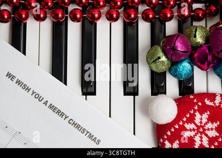 Concept de musique de Noël. Musique imprimée sur le pianto avec cloches de jingle, boules de noël rouges et chapeau. Banque D'Images