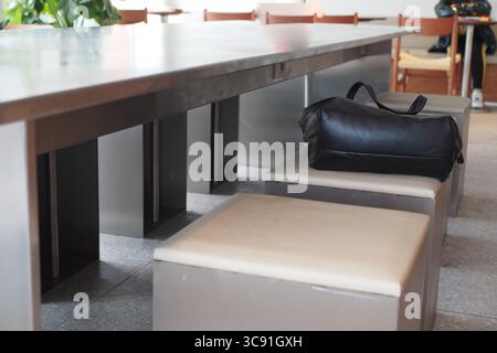 Espace café vide avec un sac noir sur un tabouret, concept de sac perdu Banque D'Images