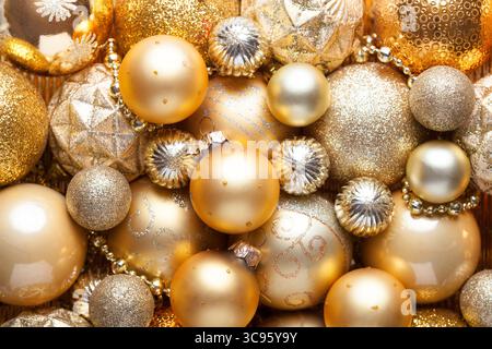 Fond de vacances de Noël avec des boules dorées brillantes. Gros plan des décorations de Noël dorées en pile de différentes tailles, nuances et textures. Pose à plat Banque D'Images