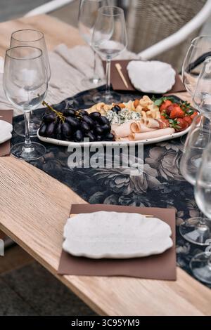 Une table magnifiquement agencée avec une délicieuse planche de charcuterie entourée d'élégantes verreries et de fruits frais, parfaite pour ramasser un Banque D'Images