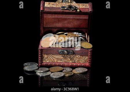 vieilles pièces de monnaie dans la poitrine sur fond noir avec des reflets. Banque D'Images