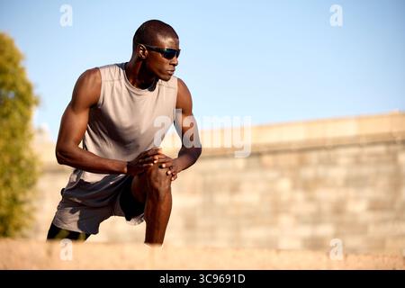 Une personne en forme effectuant un étirement à l'extérieur par temps clair, mettant l'accent sur la santé et la préparation avant l'activité physique. L'ensemble athlétique Banque D'Images