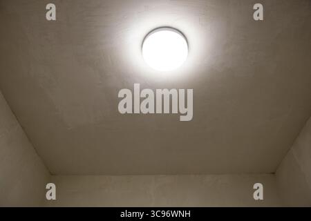 Lustre léger au plafond d'un couloir étroit avec des murs beiges et du stuc, intérieur de l'appartement avec éclairage et garniture décorative Banque D'Images