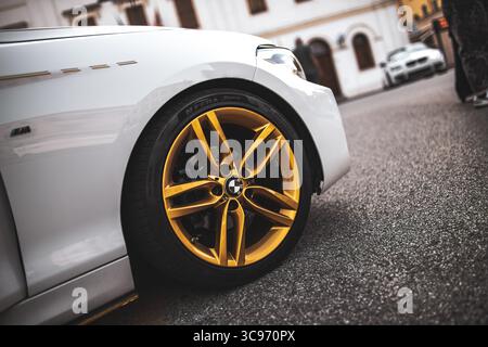 Rome, italie 5 août 2025 : jante dorée et pneu à profil bas d'une voiture de sport à réglage blanc garée sur asphalte Banque D'Images