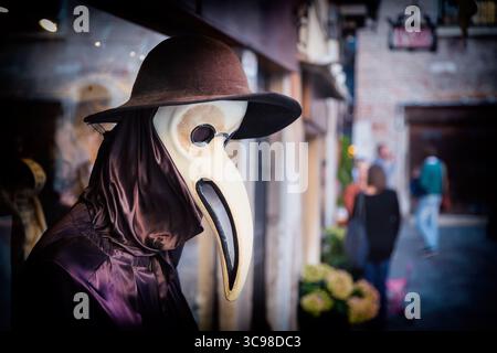 Mannequin vénitien traditionnel en costume de médecin de la peste, masque et chapeau près de la vitrine dans la rue de Venise, Italie. Image tonifiée Banque D'Images