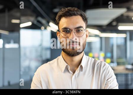 Un professionnel des affaires concentré avec des lunettes dans un cadre de bureau. La photo met en évidence une personne confiante et accessible. Banque D'Images