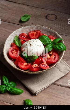 Salade de tomates avec stracciatella fromage à pâte molle et basilic sur une table en bois rustique. Repas maison sain. Banque D'Images