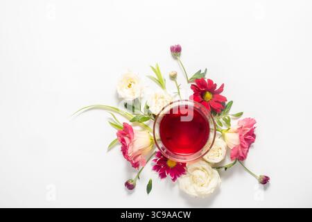 Arrangement de fleurs et une tasse de tisane sur un fond blanc. Vue de dessus et espace de copie. Roses blanches délicates et eustoma Banque D'Images