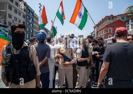 Srinagar, Inde. 05 août 2025. Des policiers indiens gardent les partisans du Bharatiya Janata Party (BJP) alors qu'ils célèbrent le sixième anniversaire de l'abrogation de l'article 370 et de la révocation du statut spécial du Jammu-et-Cachemire au centre-ville de Lal Chowk. Le gouvernement du premier ministre indien Narendra Modi a abrogé l'article 370 le 5 août 2019, mettant fin au statut spécial semi-autonome de la région. Crédit : SOPA images Limited/Alamy Live News Banque D'Images