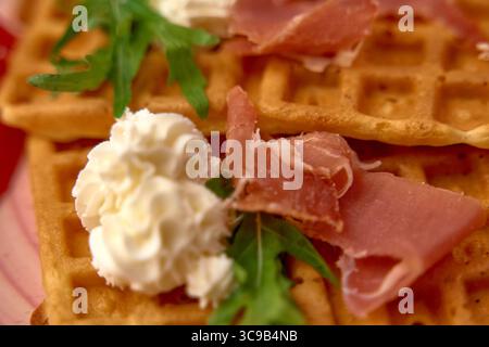 Gaufres savoureuses délicieusement confectionnées, garnies d'une garniture fouettée crémeuse et d'un prosciutto salé garni d'Arugula fraîche, pour une expérience de saveur unique Banque D'Images
