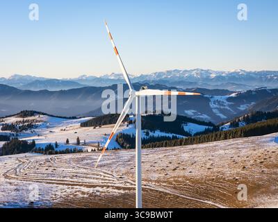 Vue aérienne d'une éolienne imposante se dresse brutalement contre les collines enneigées et les montagnes lointaines et brumeuses, Sommeralm, Steiermark, Autriche. Banque D'Images