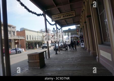 Les visiteurs se promènent le long de la promenade en bois dans le vieux Sacramento, en Californie, devant des vitrines d'époque et des bâtiments historiques sous un ciel hivernal clair Banque D'Images