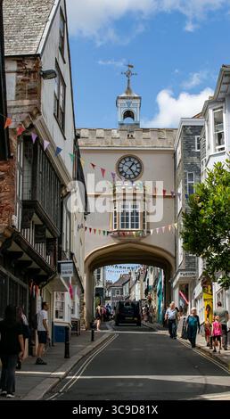 Une scène de rue pittoresque avec un bâtiment historique voûté avec une horloge et des drapeaux de guirlande sous un ciel bleu Totnes Devon UK Banque D'Images