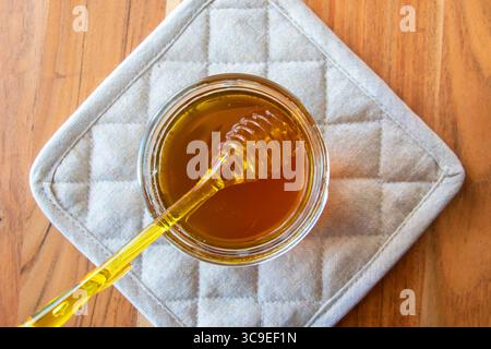Pot en verre de miel avec nid d'abeilles et cuillère jaune rester sur la table en bois. Banque D'Images