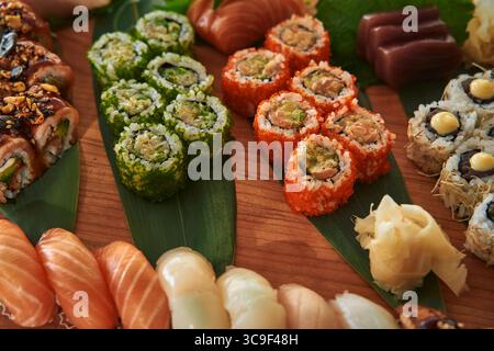 Un assortiment coloré de Sushi Rolls et de Sashimi sur un plateau en bois avec divers ingrédients et styles de présentation pour une expérience culinaire artistique Banque D'Images