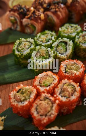 Un tableau coloré de délicieux Sushi Rolls avec des variétés enveloppées dans des algues et surmontées d'ingrédients savoureux sur une planche en bois Banque D'Images