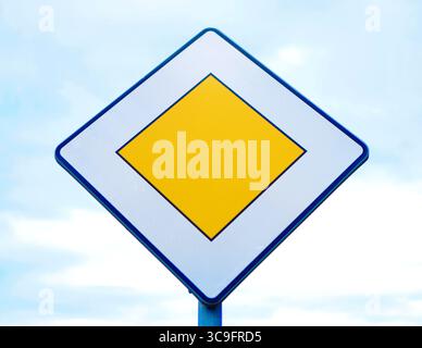 Panneau de signalisation jaune losange sur un poteau indiquant la route prioritaire devant vous. Banque D'Images
