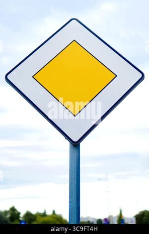 Panneau de signalisation jaune losange sur un poteau indiquant la route prioritaire devant vous. Banque D'Images