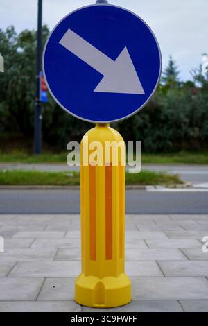 Panneau rond bleu avec une flèche blanche pointant vers la droite, indiquant les instructions obligatoires de maintien à droite. Banque D'Images