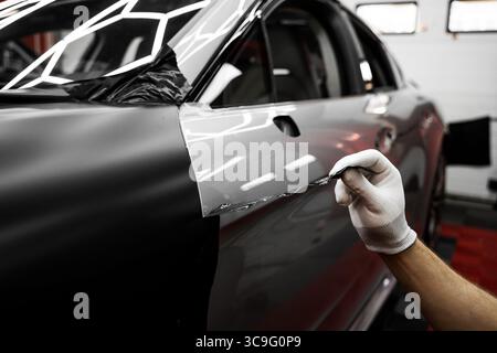 L'application d'habillage modifie l'apparence du véhicule. Emballage en vinyle pour voiture à panneau complet. L'installation à grande échelle de film vinyle transforme l'extérieur du véhicule Banque D'Images