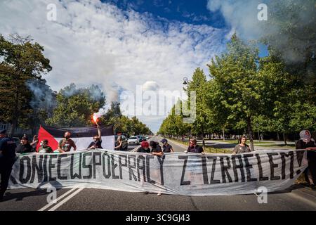Les manifestants pro-palestiniens bloquent la route avec une banderole, en polonais, qui dit : « fin de la coopération avec Israël ! » pendant la démonstration. Dans l'après-midi du 5 août, la veille de la prestation de serment du nouveau président polonais, des militants pro-palestiniens ont bloqué la route devant la Chancellerie du premier ministre polonais à Varsovie. Les manifestants appellent à la fin de la coopération du gouvernement avec le gouvernement sioniste de droite d'Israël. Les manifestants ont bloqué la route avec une banderole et des fusées éclairantes avant que la police ne les emmène sur le bord de la route, où la manifestation a continué. Banque D'Images