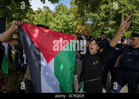 Un manifestant fait des gestes tout en tenant le drapeau palestinien pendant la manifestation. Dans l'après-midi du 5 août, la veille de la prestation de serment du nouveau président polonais, des militants pro-palestiniens ont bloqué la route devant la Chancellerie du premier ministre polonais à Varsovie. Les manifestants appellent à la fin de la coopération du gouvernement avec le gouvernement sioniste de droite d'Israël. Les manifestants ont bloqué la route avec une banderole et des fusées éclairantes avant que la police ne les emmène sur le bord de la route, où la manifestation a continué. Banque D'Images