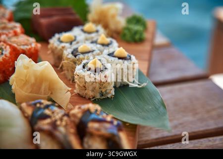Un tableau coloré de variétés de sushi présentant des ingrédients frais, des saveurs et de l'art culinaire sur une planche en bois parfaite pour dîner et partager Banque D'Images