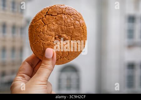 La main d une femme tient un biscuit traditionnel aux amandes avec un fond d architecture baroque ottomane de la ville à Istanbul, en Turquie Banque D'Images