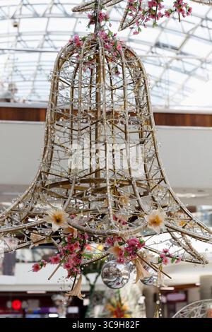 Un lustre décoratif en forme de cloche fait de matériaux tissés, orné de fleurs et de cristaux suspendus. Il est affiché dans un espace intérieur lumineux avec Banque D'Images